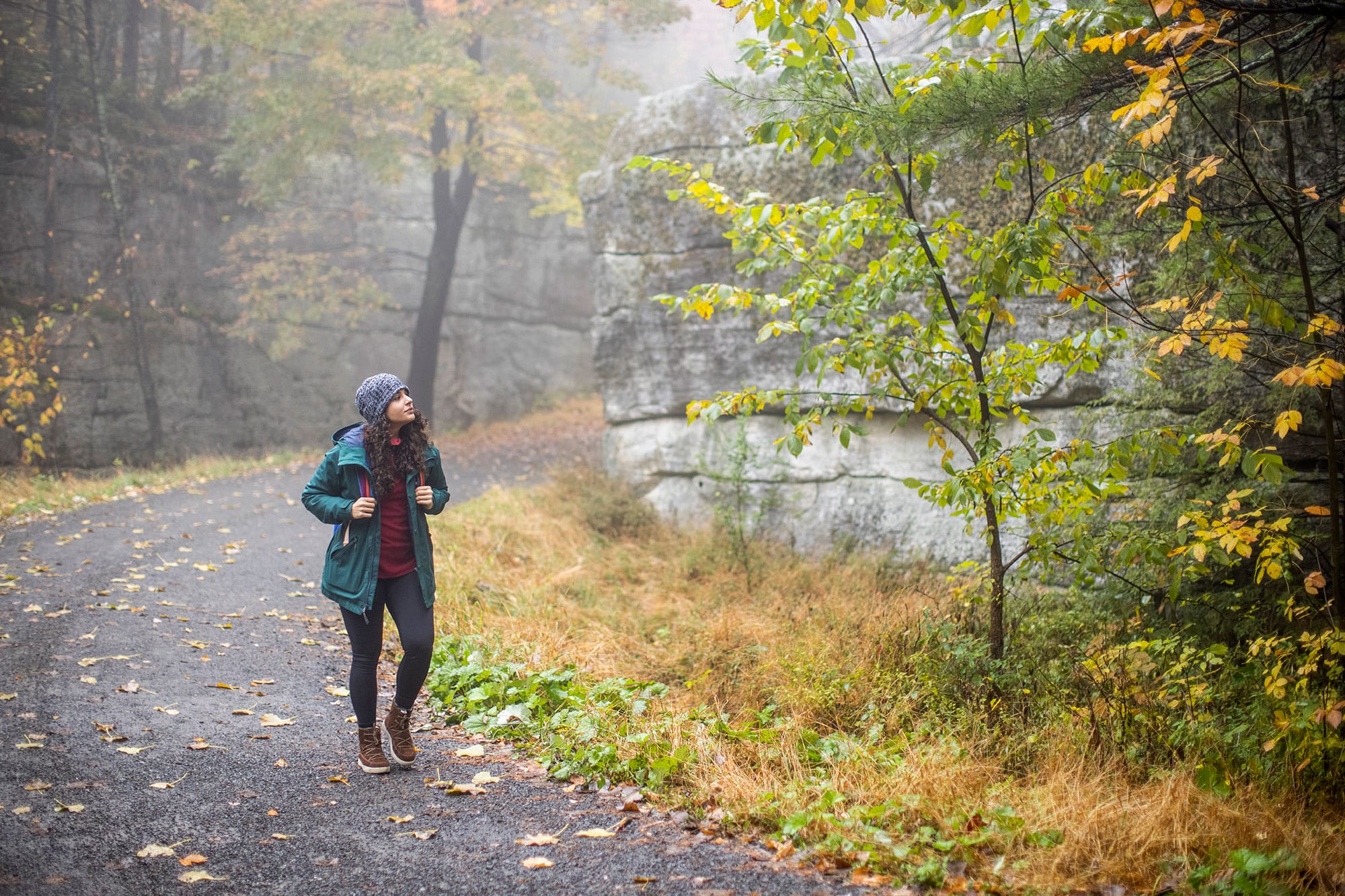 A woman walking down a trail in the fall.