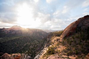 The sun is shining over a canyon in zion national park.