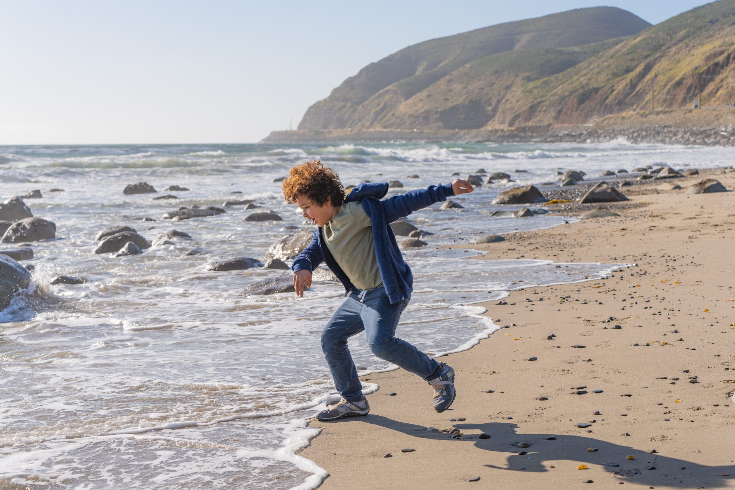 A boy is running on a beach.
