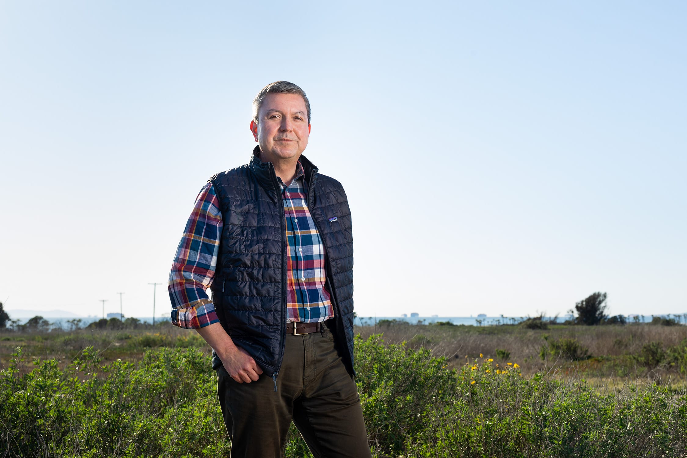 A man in a plaid shirt standing in a field.