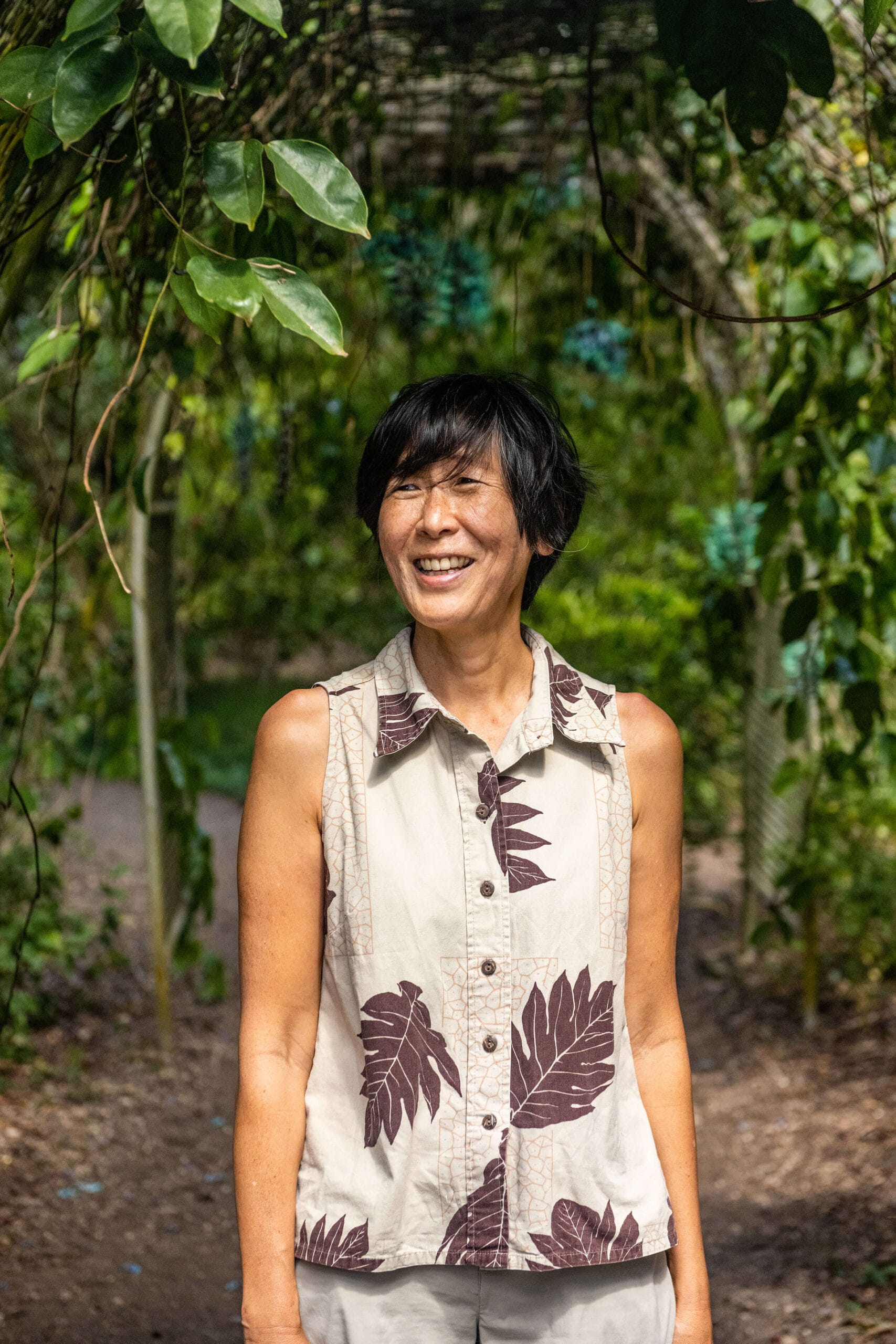 An asian woman smiling in front of an arboretum.