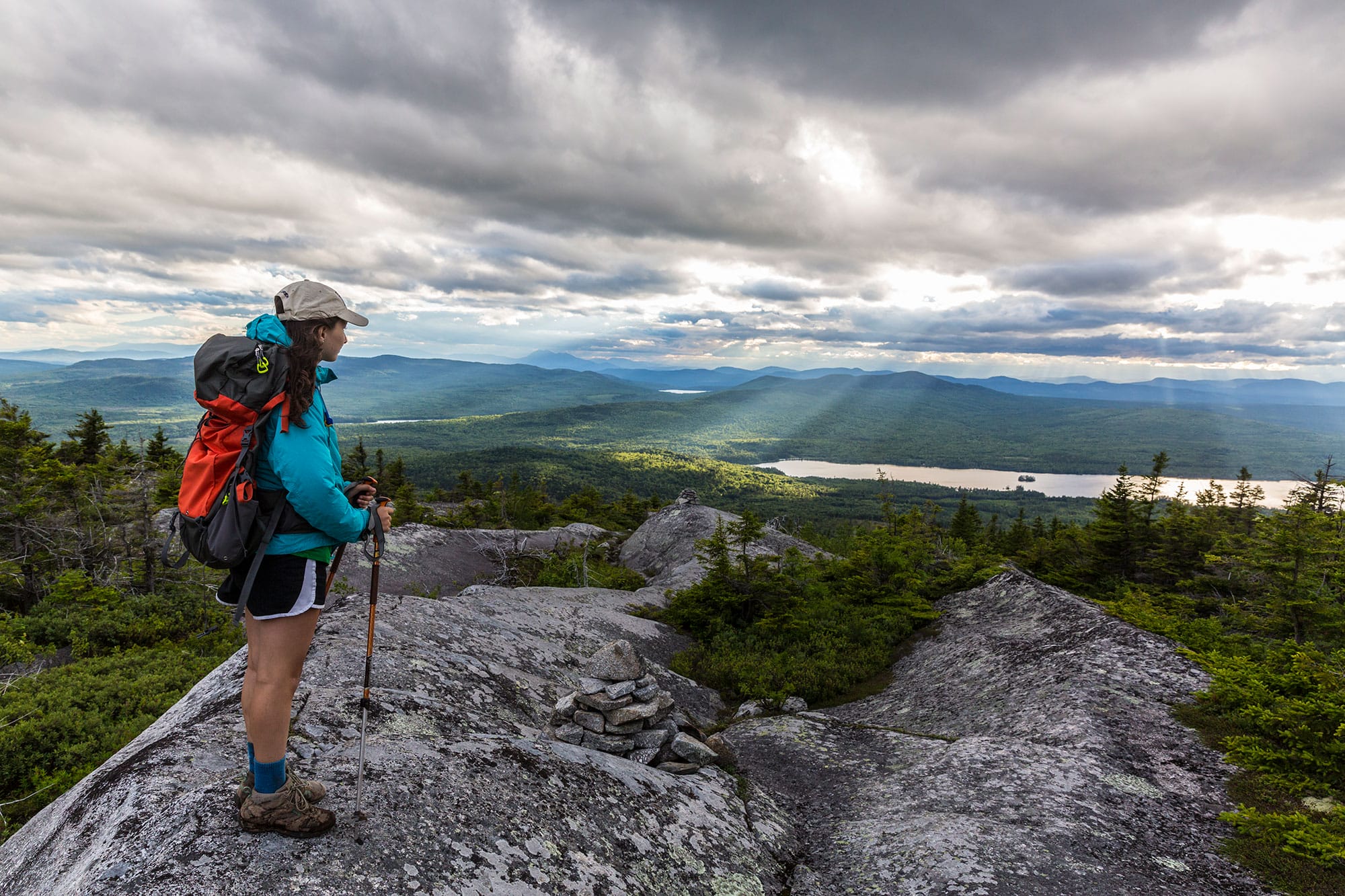 A woman is standing on top of a mountain.