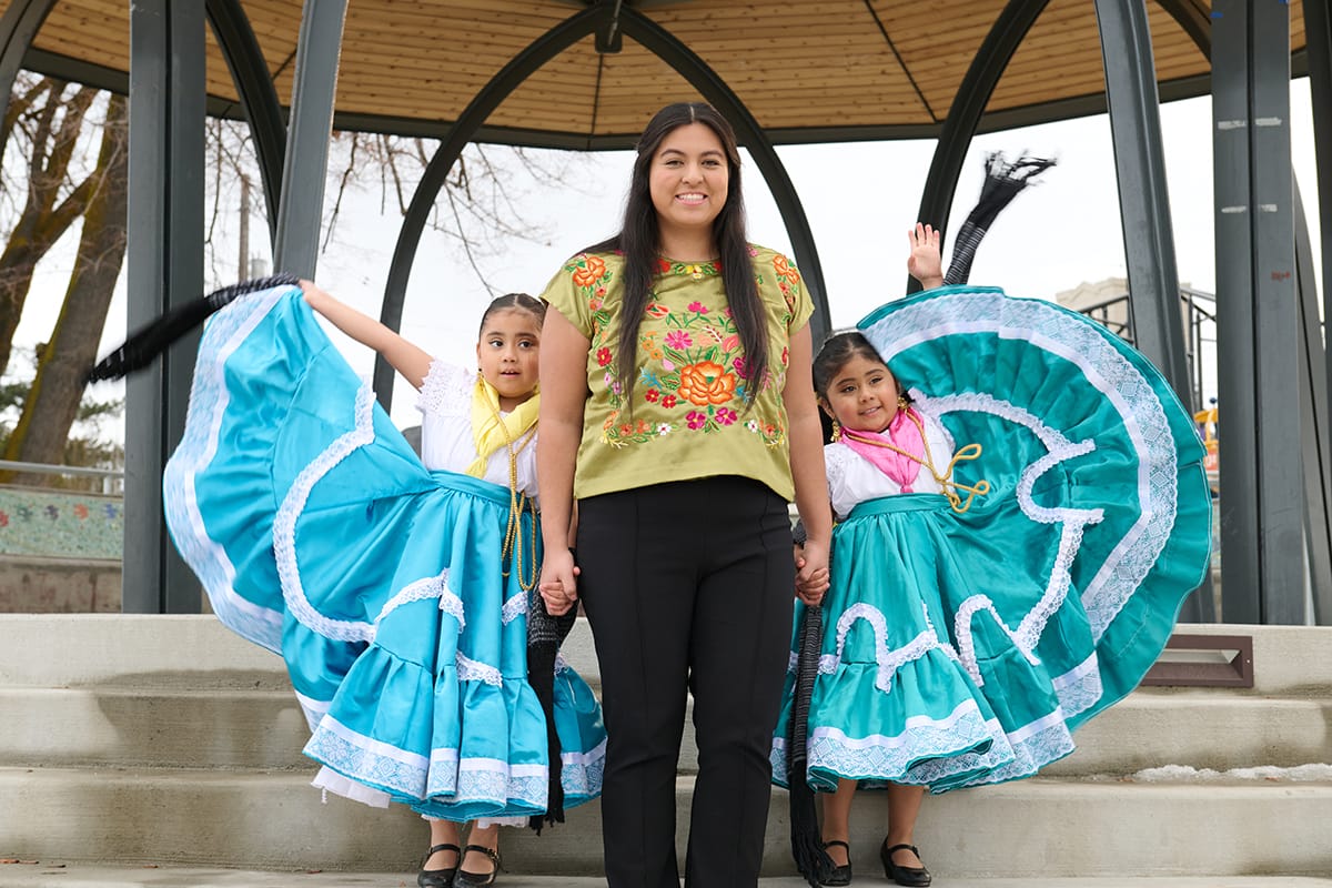 A woman in a mexican dress poses with her children.