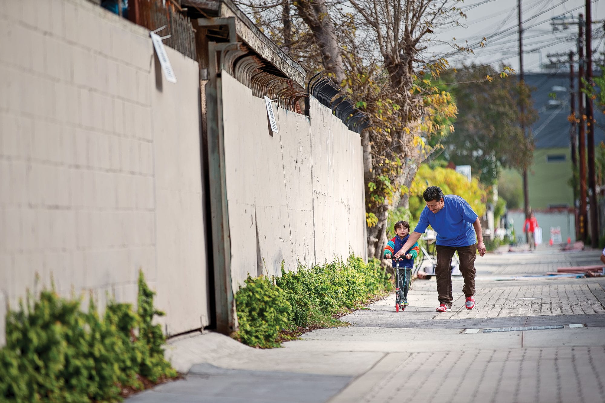 A man and a child walking down a sidewalk.