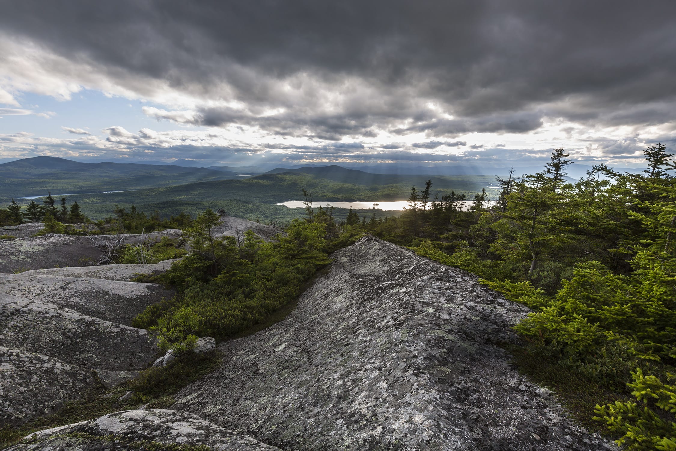 The view from the top of a rocky mountain overlooking a lake.