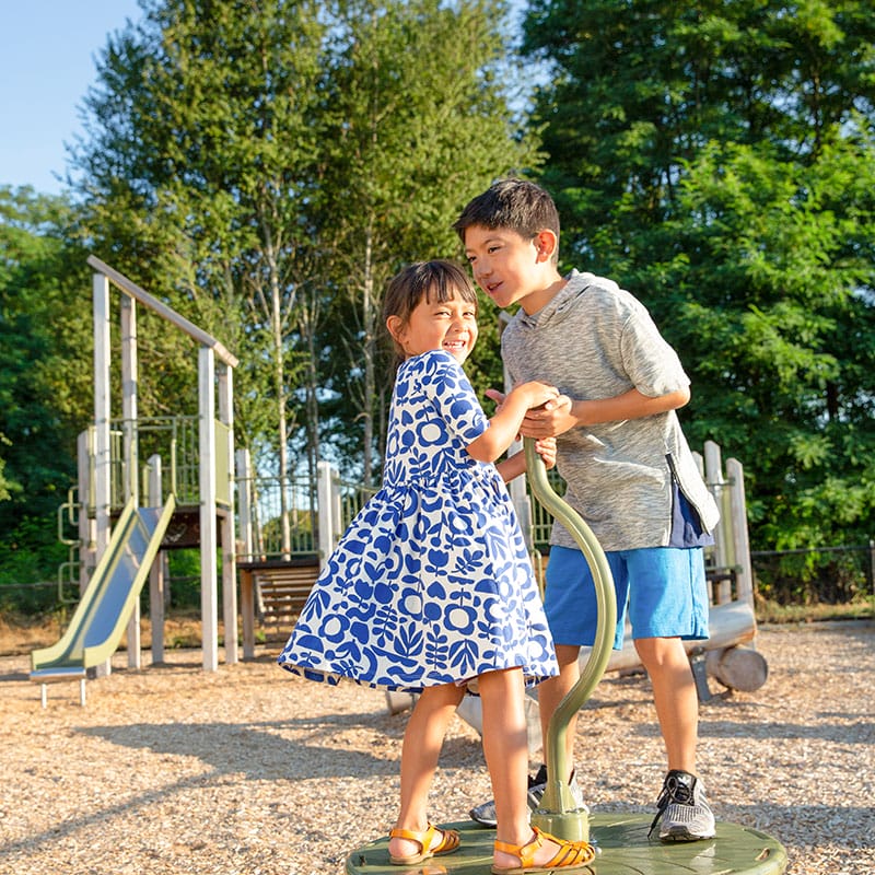 A boy and a girl standing on a playground equipment.