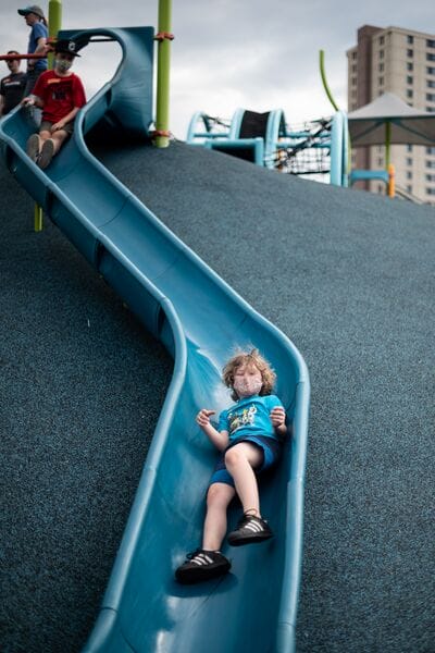 A boy slides down a blue slide at a playground.