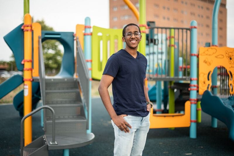 A young man standing in front of a playground.