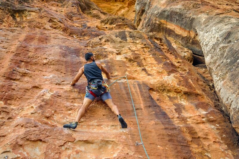 A man is climbing up the side of a canyon.
