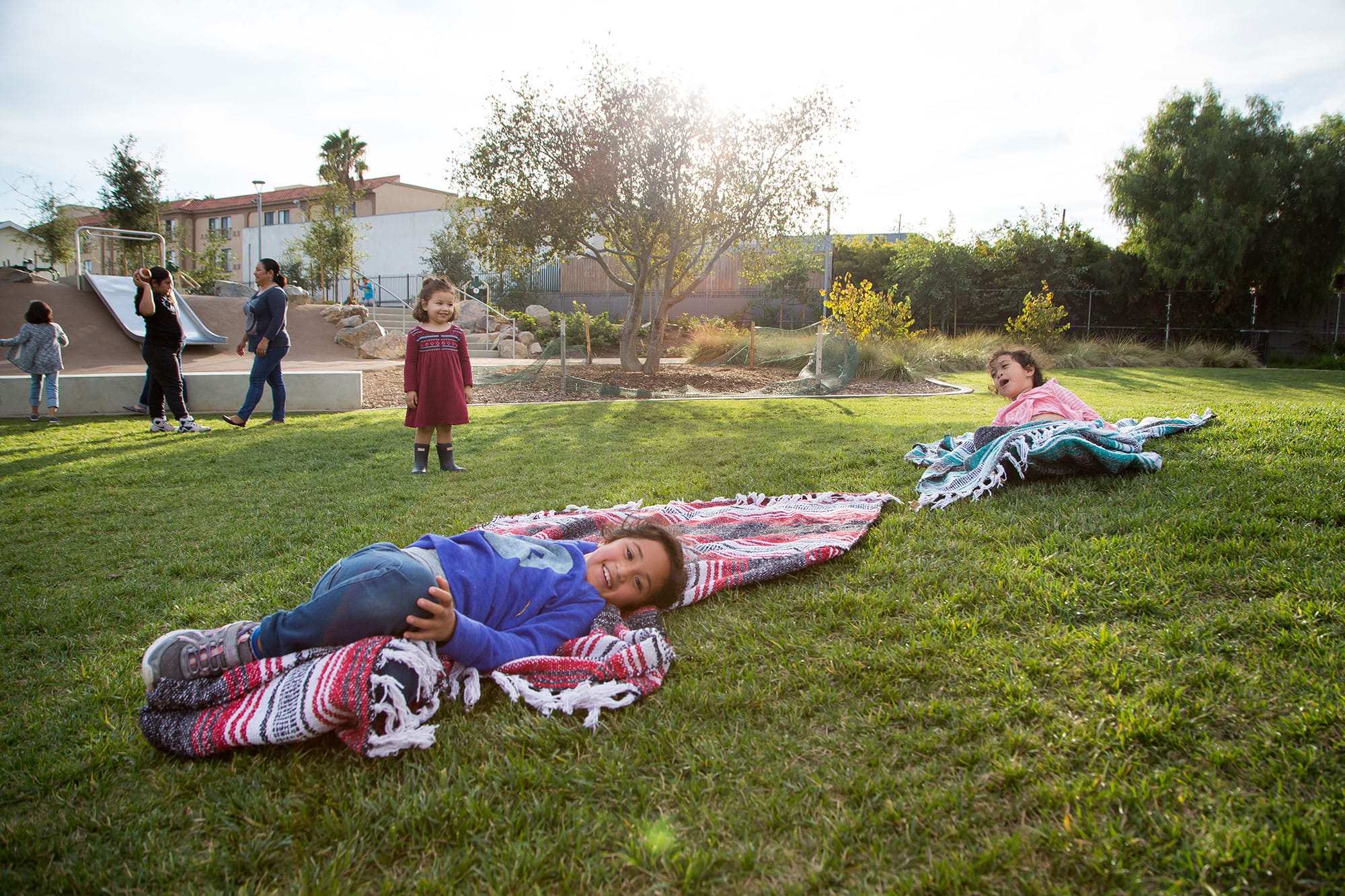 A group of children laying on blankets in the grass.