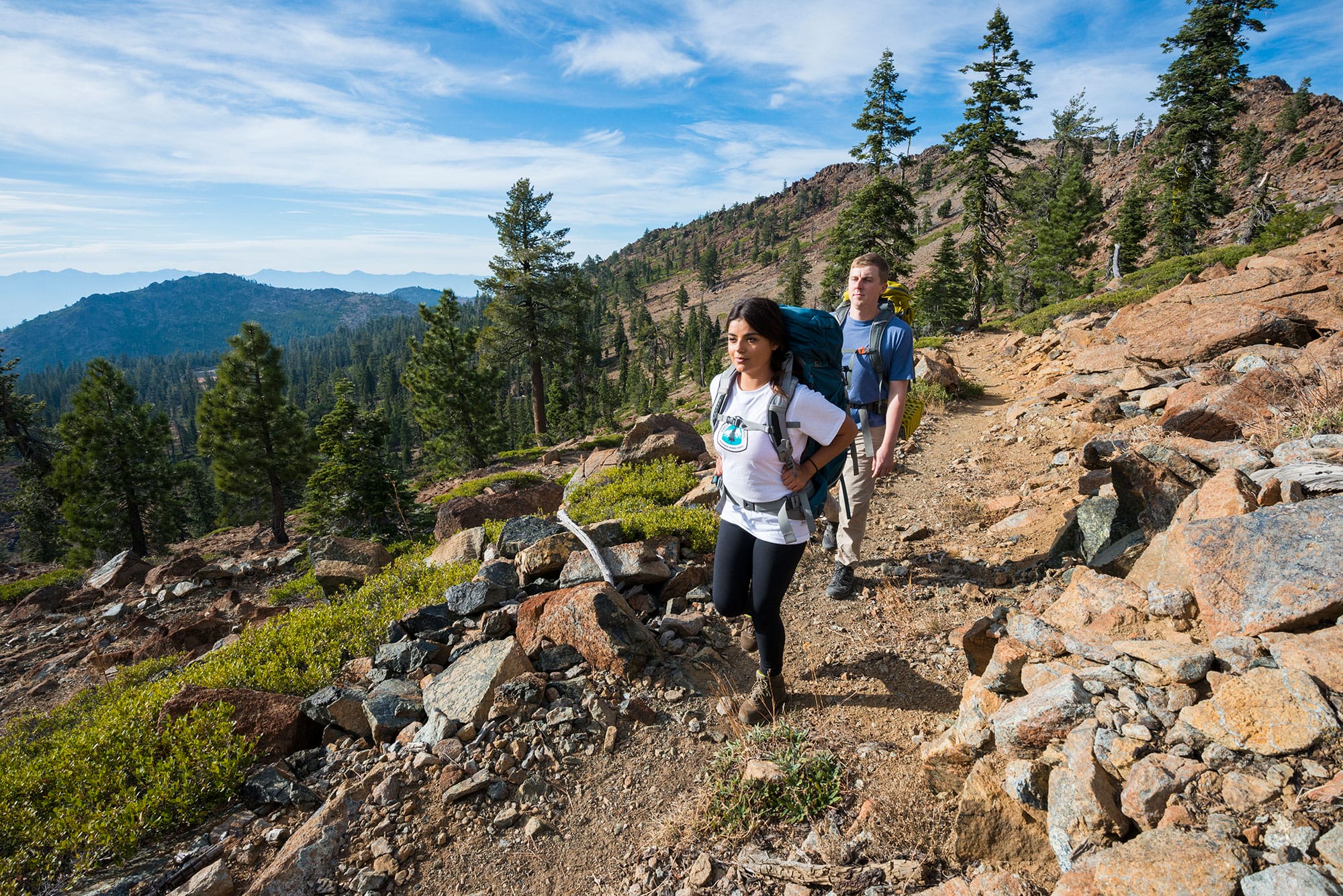 Two people hiking on a rocky trail.