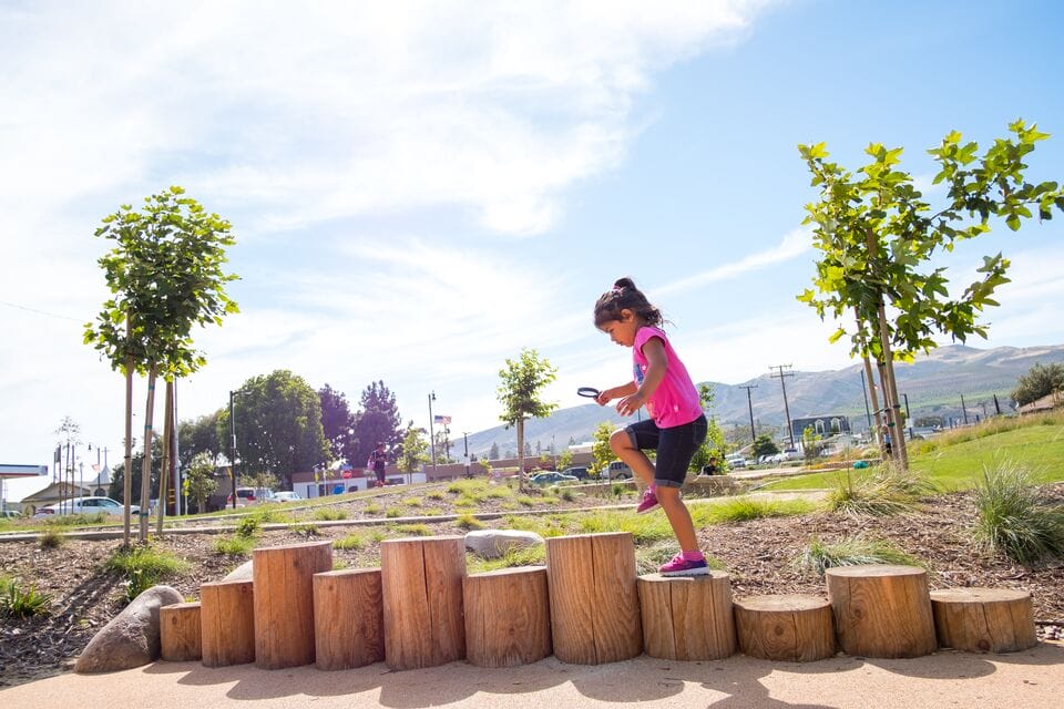 A girl is playing on wooden steps in a park.