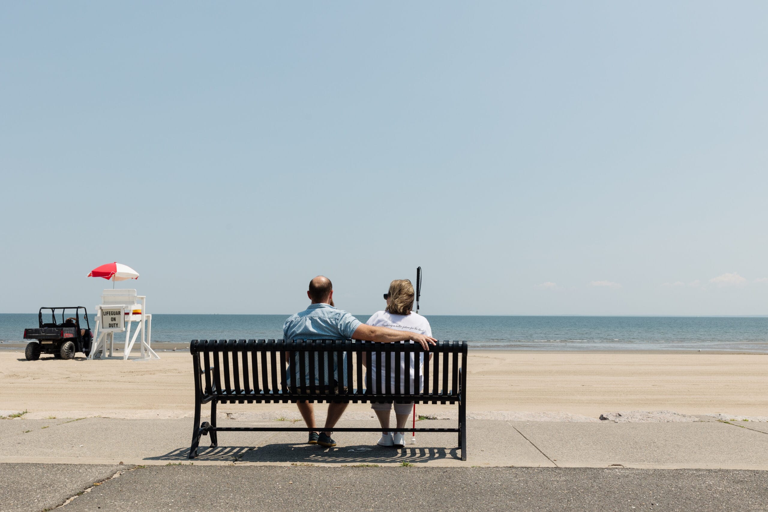 A couple sitting on a bench on the beach.