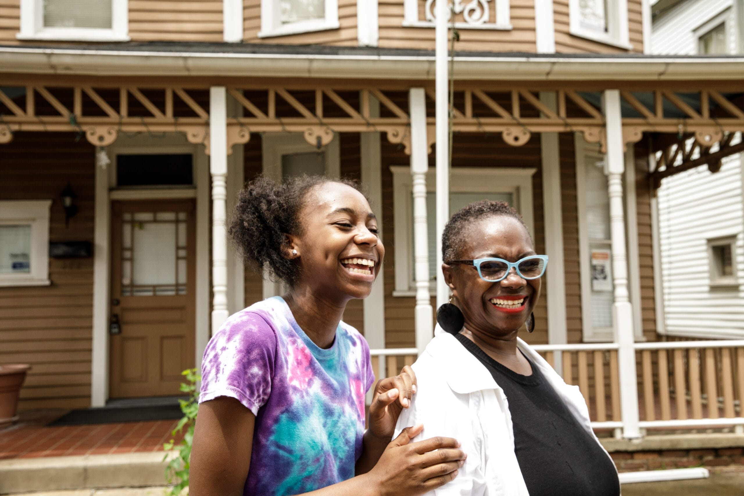 Two women smiling in front of a house.