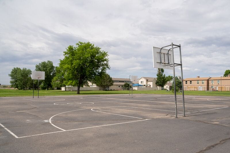 A basketball court in the middle of an empty lot.