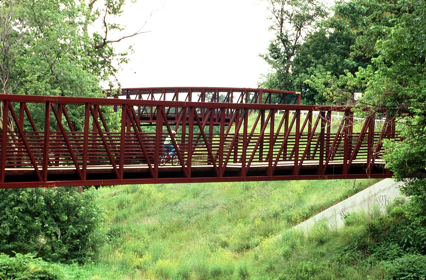A biker travels across one of the red steel bridges on the Gwynns Falls Trail in Baltimore, MD. Photo: Maria Carolla