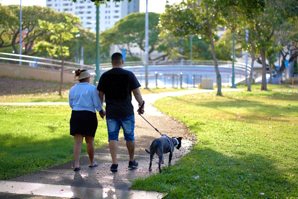 A couple walks their dog in ʻAʻala Park in Hawaii