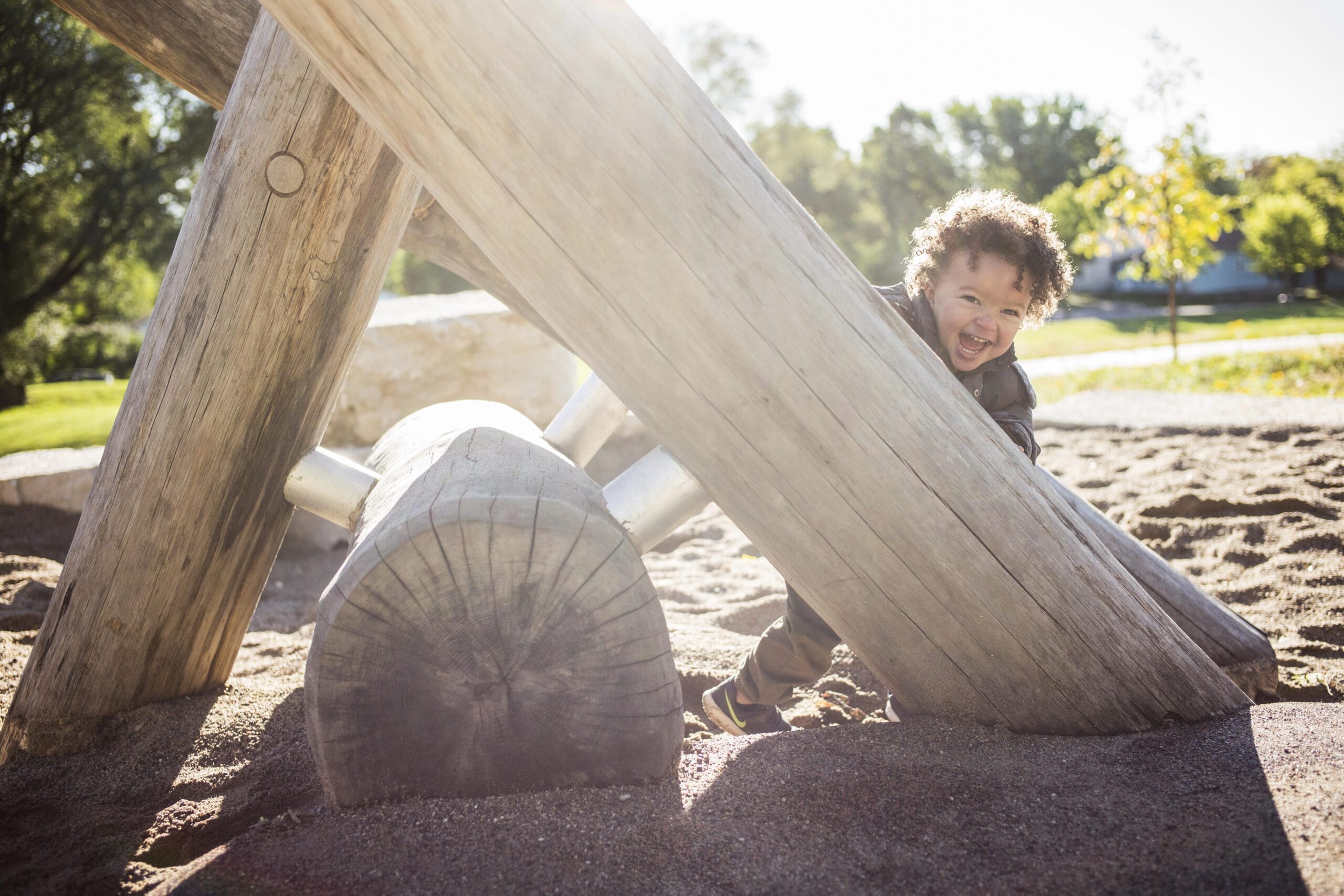 Toddler smiles and plays on play structure in a park in St. Paul.